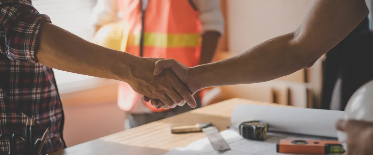 two people shaking hands during a meeting on construction project